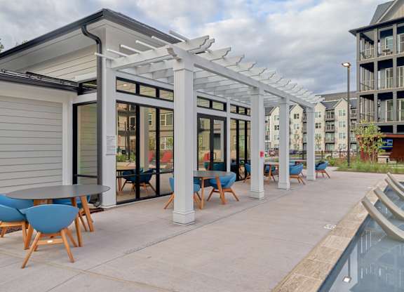 A patio with a table and chairs is covered by a white pergola.