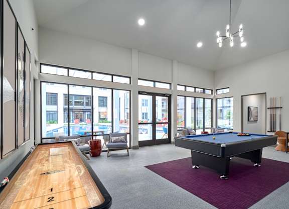 A billiard table is in the middle of a room with a pool table and a foosball table.