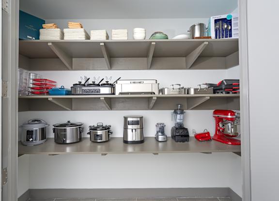 A kitchen pantry with a red mixer on the bottom shelf.