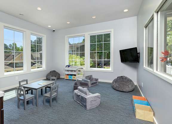 A sunny day outside the windows of a white room with grey carpeting and furniture.