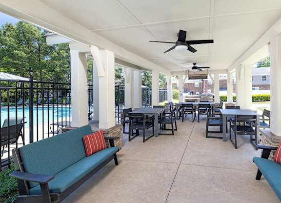 A patio with a table and chairs and a ceiling fan.