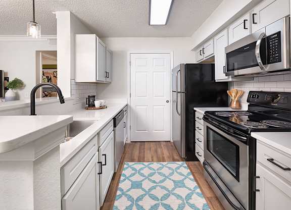 A kitchen with black appliances and white cabinets.