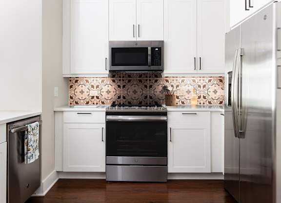 a white kitchen with stainless steel appliances and white cabinets