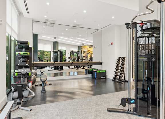 A gym with a variety of equipment including treadmills, weights, and exercise machines.