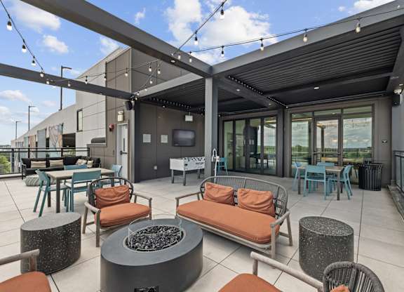 A patio with a fire pit and chairs.