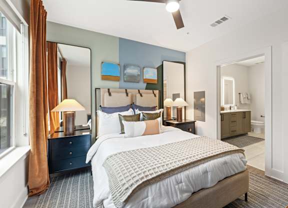 A bedroom with a large bed and a dresser with a mirror above it.