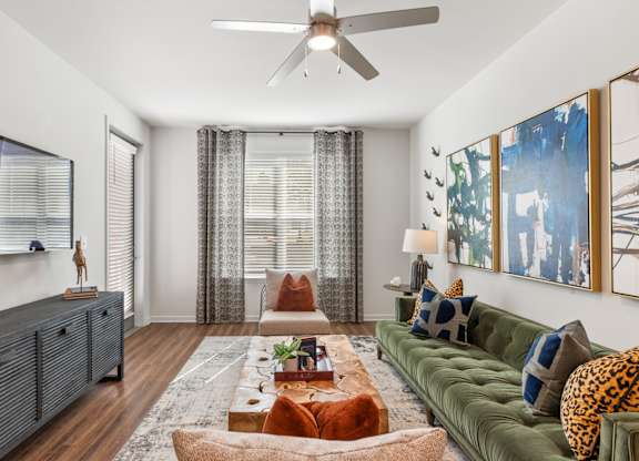 A living room with a green couch and a wooden floor.