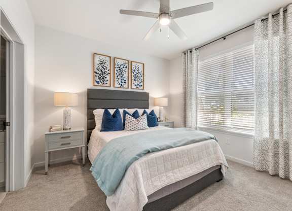 A bedroom with a bed, nightstand, and a ceiling fan.