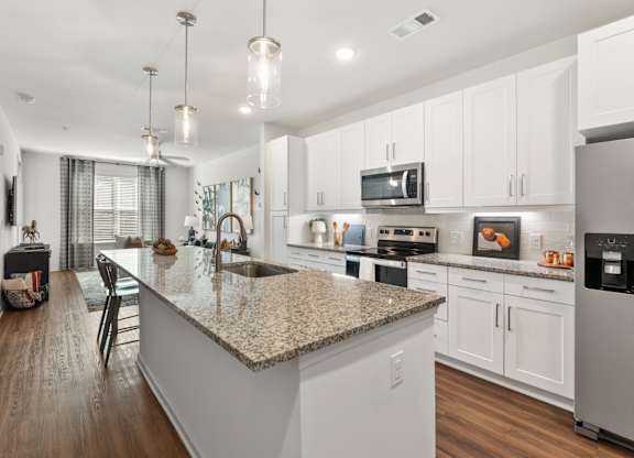 A modern kitchen with a granite countertop and stainless steel appliances.