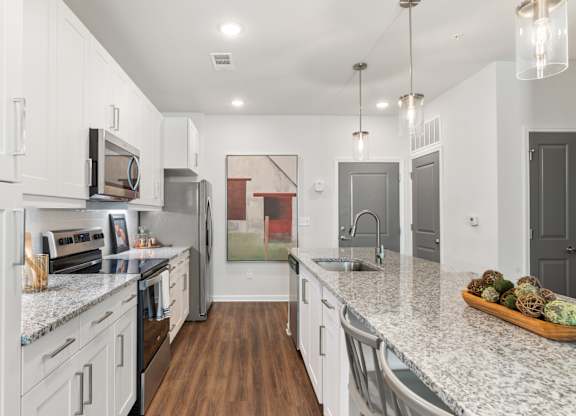 A kitchen with white cabinets and a marble countertop.