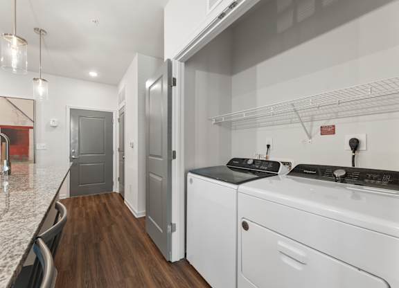 A modern kitchen with white appliances and a marble countertop.