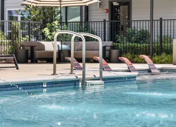 A pool with a ladder and a sun umbrella.