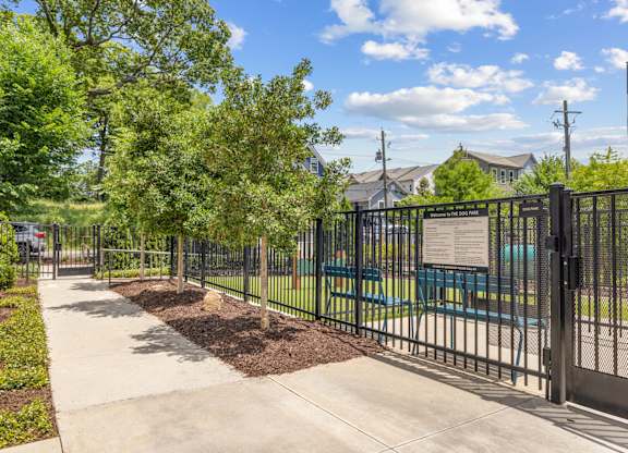 A black metal fence surrounds a green park area.