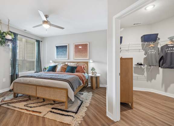 A bedroom with a bed, a rug, a ceiling fan and a wardrobe.