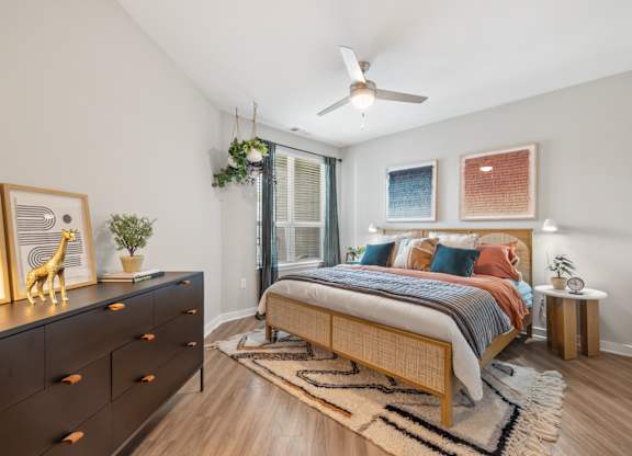 A bedroom with a bed, dresser, and ceiling fan.