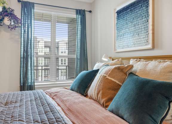 A bedroom with a large bed and a window with curtains.