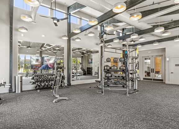 A gym with a variety of equipment including weights and cardio machines.