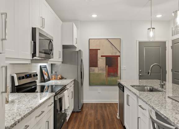 A kitchen with white cabinets and a painting hanging on the wall.