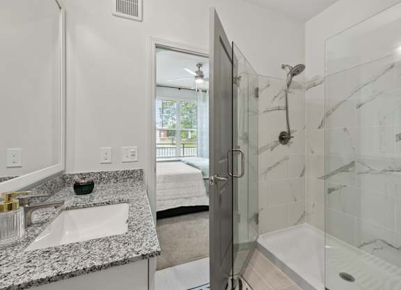 A bathroom with a marble countertop and a walk-in shower.