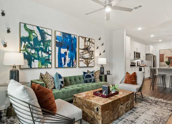 A living room with a green couch, a coffee table, and a painting on the wall.
