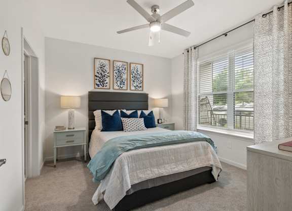A bedroom with a bed, nightstand, and a ceiling fan.