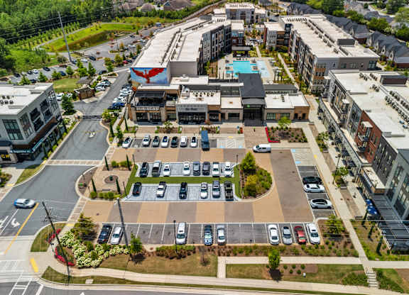 A parking lot with cars and a building with a blue pool in the background.
