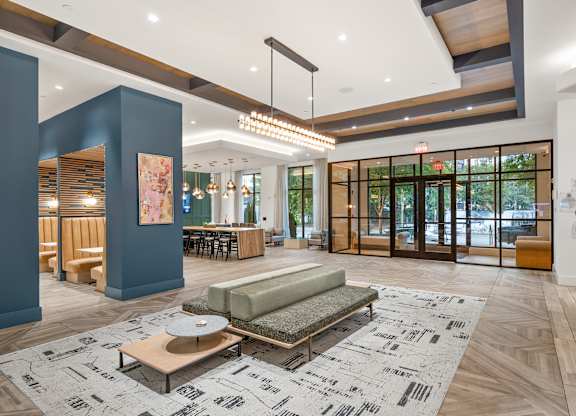 A spacious lobby with a patterned rug and a green sofa.