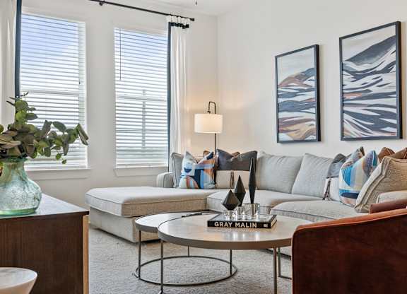A living room with a grey sofa, a coffee table, and two framed pictures on the wall.