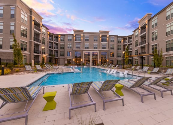 a swimming pool with chaise lounge chairs and a building in the background