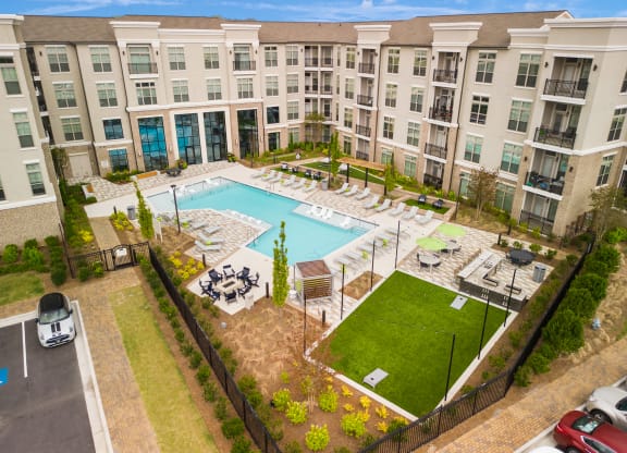 an aerial view of the resort style pool with chaise lounge chairs and grassy area