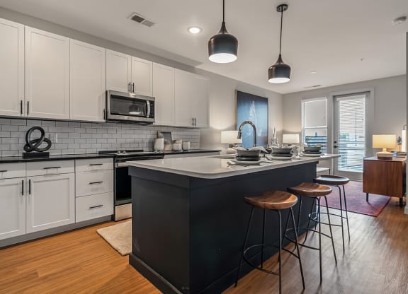 an open kitchen with a large island with three stools