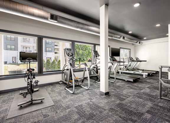 A gym with a variety of equipment including treadmills, stationary bikes, and weight machines.