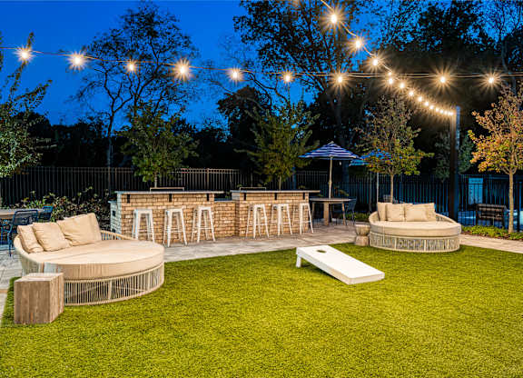 A backyard with a patio, lawn, and string lights.