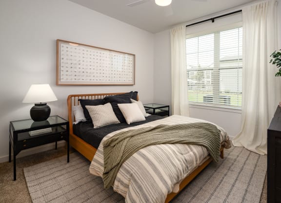 a bedroom with a bed and a window with white curtains