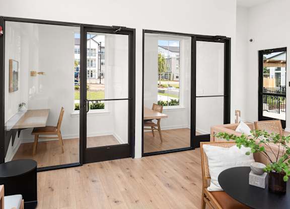 A black table with a plant on it sits in front of a glass door.
