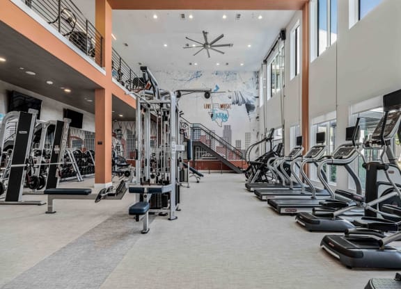 a gym with cardio equipment and a mural on the wall