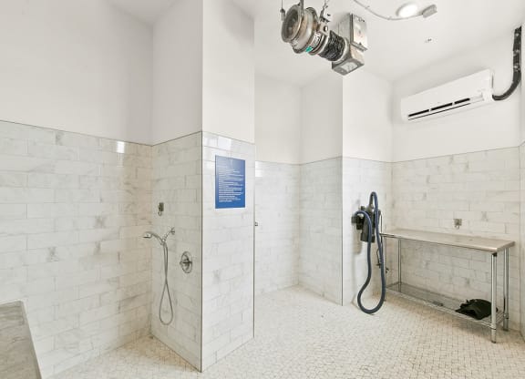 a large white tiled bathroom with a shower and a sink