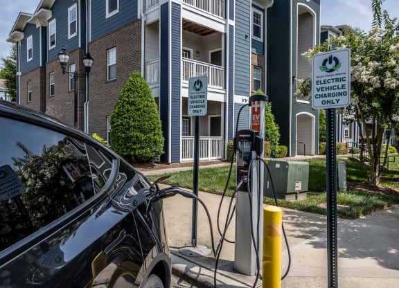 a car is plugged into a charging station in front of an apartment building