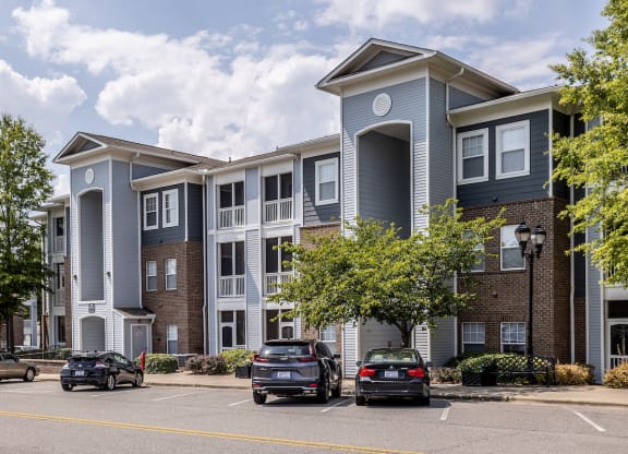 a large apartment complex with cars parked in front of it