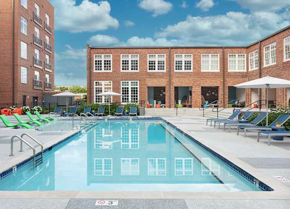 a swimming pool with lounge chairs in front of a building