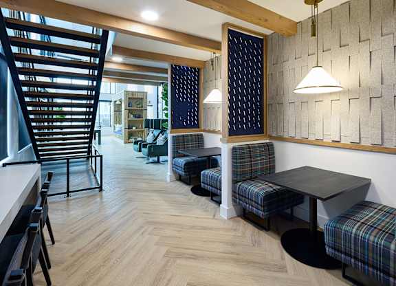 A room with a wooden floor and a wall with a patterned tile design.