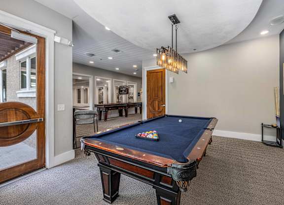 A pool table in a room with a light hanging above it.