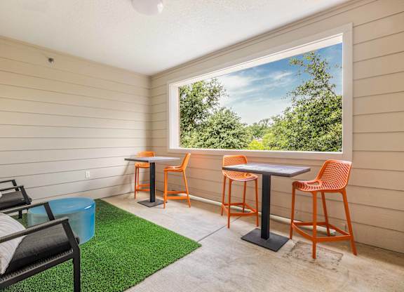 A patio with a table and chairs overlooking a green area.