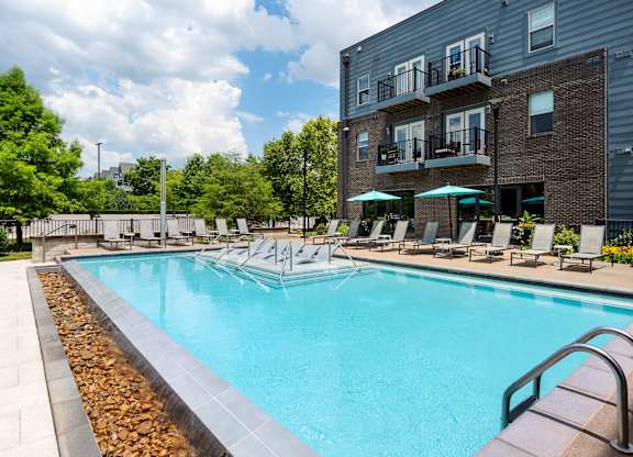 A large swimming pool surrounded by lounge chairs and umbrellas.