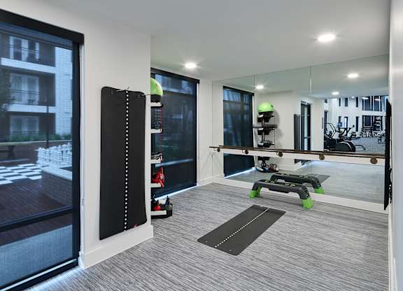 A modern room with a large mirror, a yoga mat, and a view of a building outside.