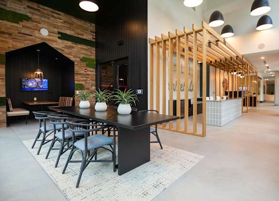 a large dining room with a black table and chairs and a tv on the wall