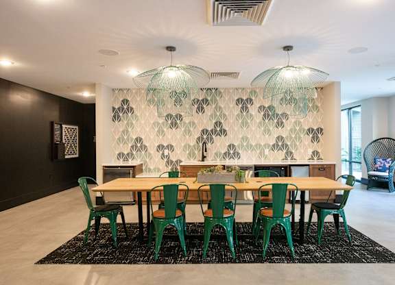 a large dining room with a wooden table and green chairs