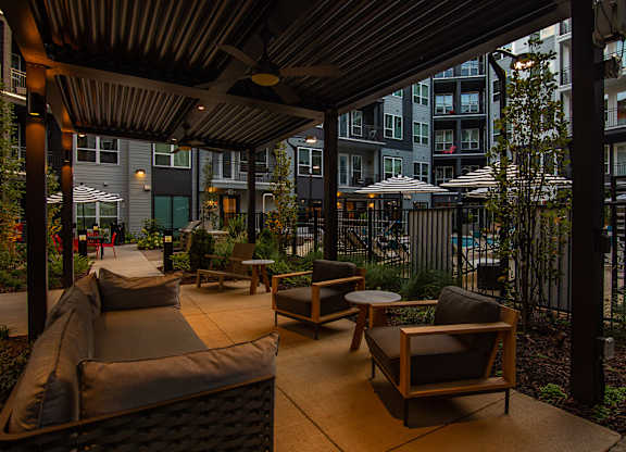 a patio with a couch and chairs and tables in front of an apartment building