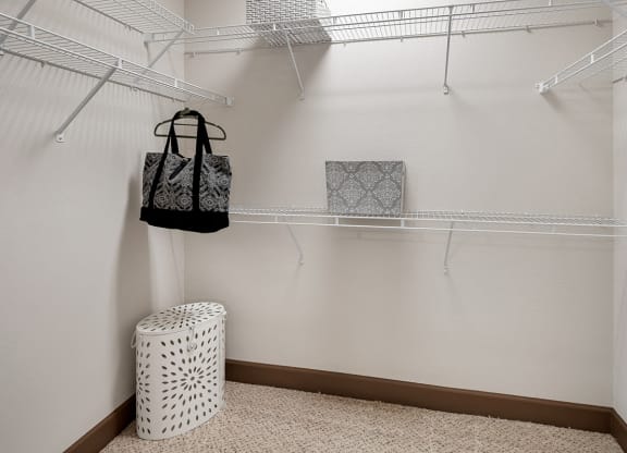 a walk in closet with a basket and bags hanging on a rack