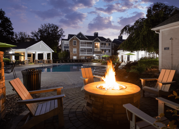 a fire pit in the middle of a backyard with a swimming pool
